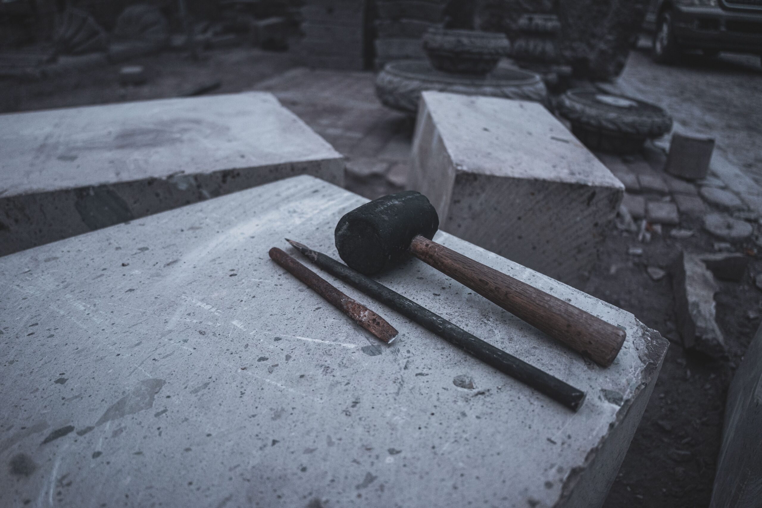 Close-up of hammer and chisels on concrete blocks in an urban setting.